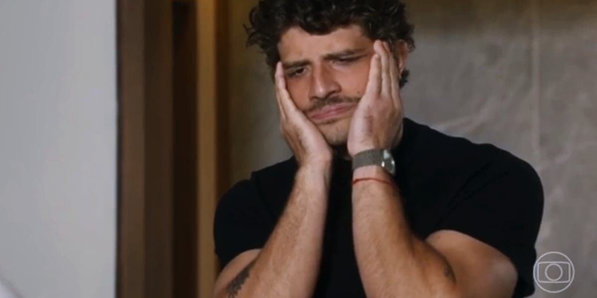 Ari, homem branco com as mãos no rosto e usando camisa preta, em cena da novela Travessia Ari, homem branco com as mãos no rosto e usando camisa preta, em cena da novela Travessia