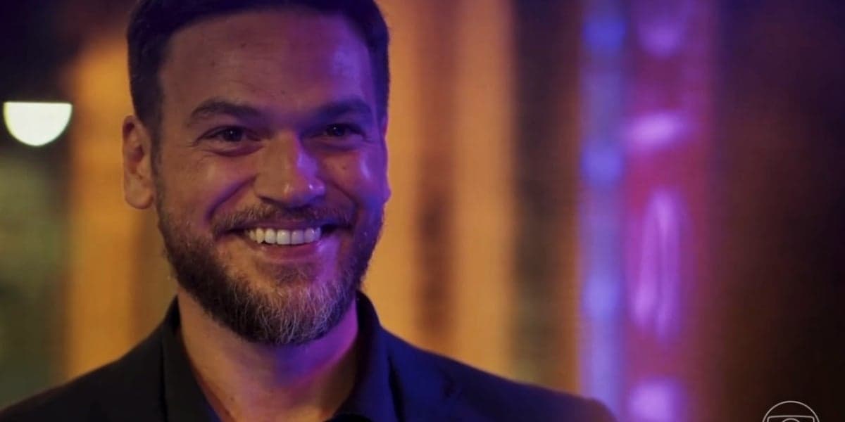 Theo sorrindo em uma cena noturna em Vai na Fé