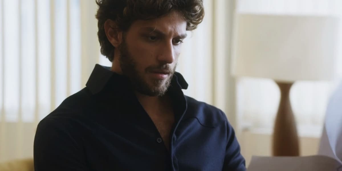 Ari em cena da novela Travessia segurando papéis