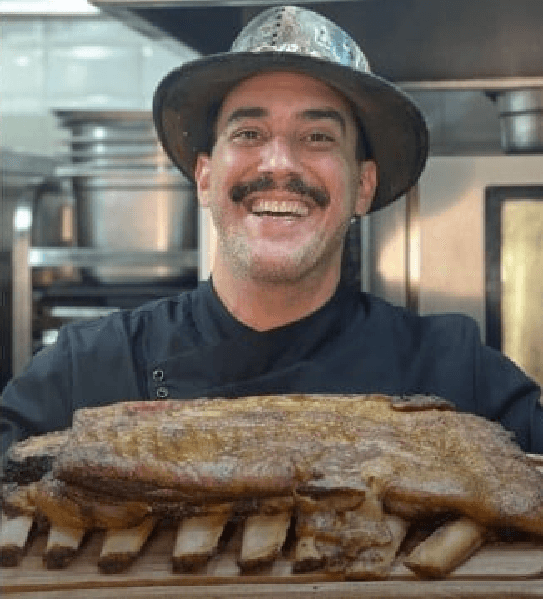 André Marques na cozinha com uma costela em mãos (Foto: Reprodução/ Internet) André Marques na cozinha com uma costela em mãos (Foto: Reprodução/ Internet)