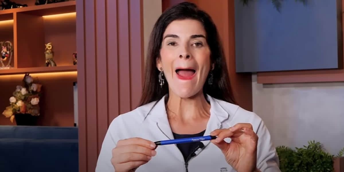 Contraia a boca e coloque a caneta entre os lábios (Reprodução: Youtube) Contraia a boca e coloque a caneta entre os lábios (Reprodução: Youtube)