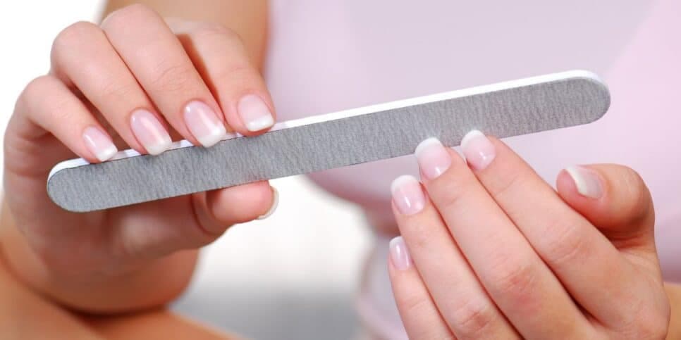 Mulher lixando unhas (Foto: Canva)