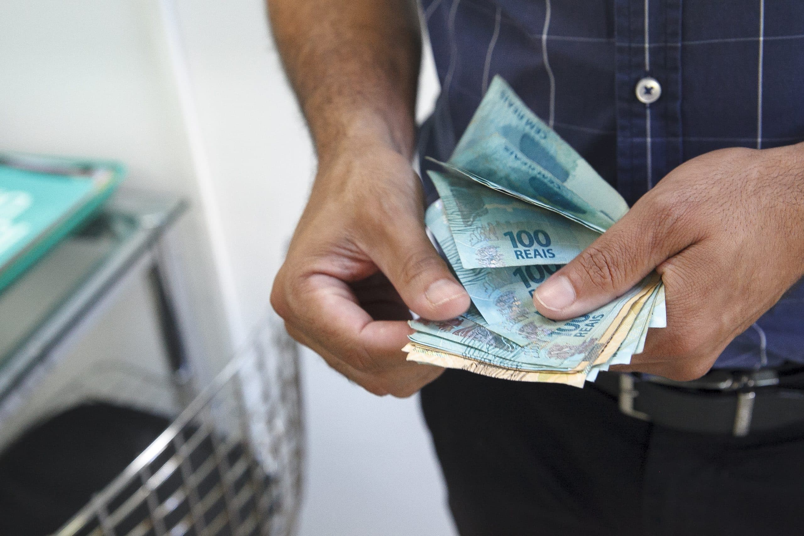 Trabalhador recebendo o salário mínimo em notas de cem reais e cinquenta reais - Foto Reprodução Internet Trabalhador recebendo o salário mínimo em notas de cem reais e cinquenta reais - Foto Reprodução Internet